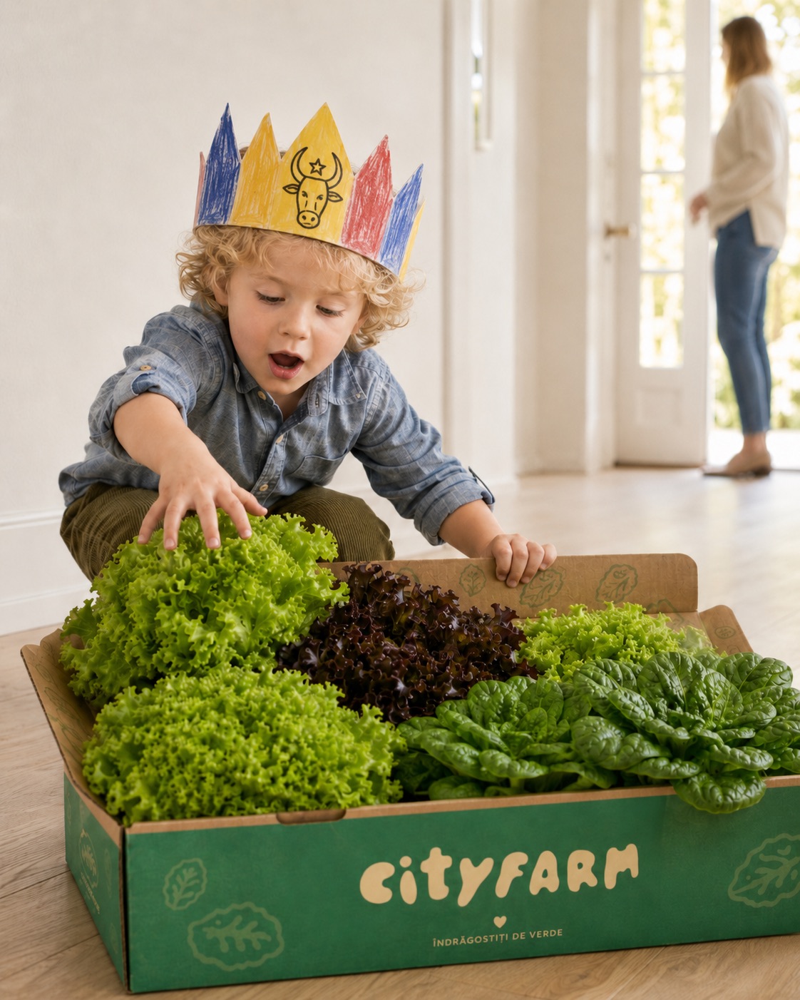 A child in a paper crown next to a CityFarm box full of fresh lettuce and greens